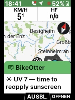 Photo of an ELEMNT screen mid-ride: a BikeOtter notification reading “UV 7 — time to reapply sunscreen” over the map.